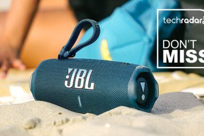 Blue JBL Charge 6 Bluetooth speaker sitting in sand