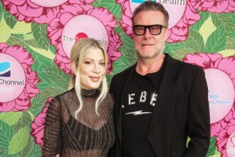 Tori Spelling and Dean McDermott posing together on the red carpet, smiling for cameras while dressed in formal attire at a Hollywood event.