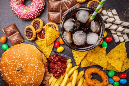 A selection of ultra-processed foods, including crisps, chocolates, and burgers, illustrating common convenience snacks and meals.
