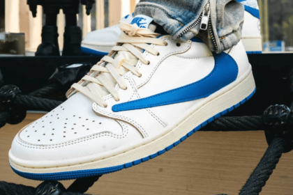 Close-up of a white and blue Nike Air Jordan sneaker with laces and perforated toe, displayed on a black rope platform
