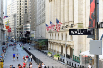 A bustling view of Wall Street with stock exchange buildings and pedestrians in New York City.